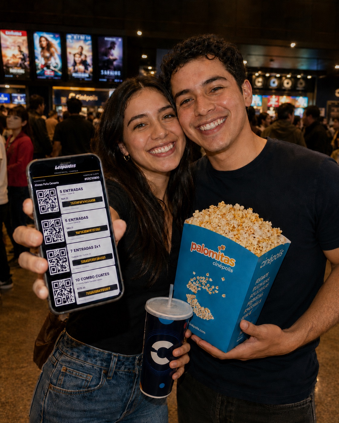 Pareja feliz en Cinépolis mostrando su cuponera digital en el celular, con palomitas y refresco
